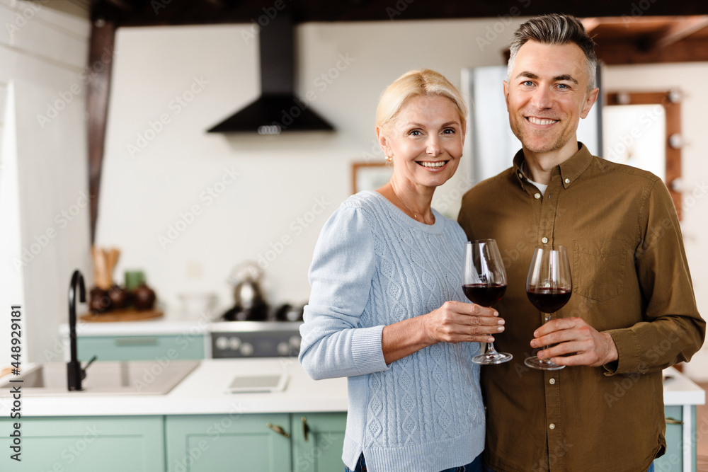 Smiling mid aged couple drinking red wine