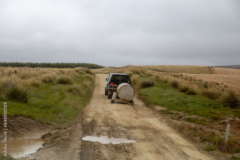 A farm vehicle towing a fuel tank along a remote country dirt road, loses a wheel along a section that is particularly bumpy and rough. South Island, New Zealand