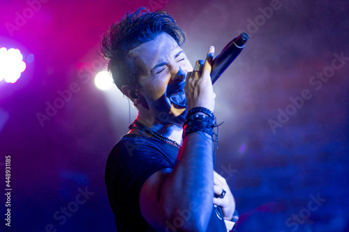 Young energetic singer performing in a club under colorful led lights photo