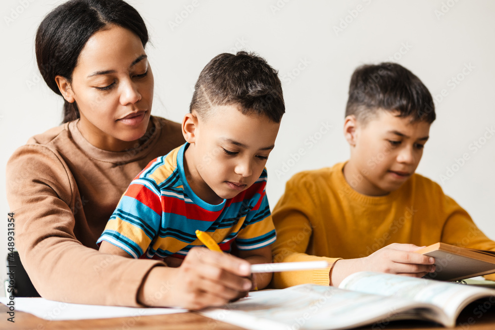 Two boys doing homework with their mother at home Two boys doing homework with their mother at home