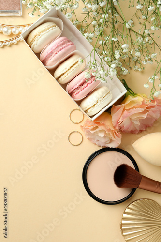 Female accessories and macaroons on beige background