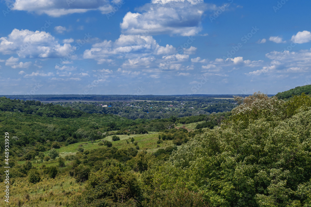 Rural landscape with green fields and sparsely wooded areas. Beautiful summer landscape with fields and green vegetation under a blue sky with white cumulus clouds in the countryside. Rural landscape with green fields and sparsely wooded areas. Beautiful summer landscape with fields and green vegetation under a blue sky with white cumulus clouds in the countryside.