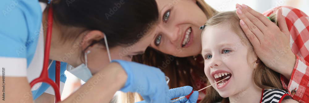 Doctor taking buccal dna swab from little girl in clinic Doctor taking buccal dna swab from little girl in clinic