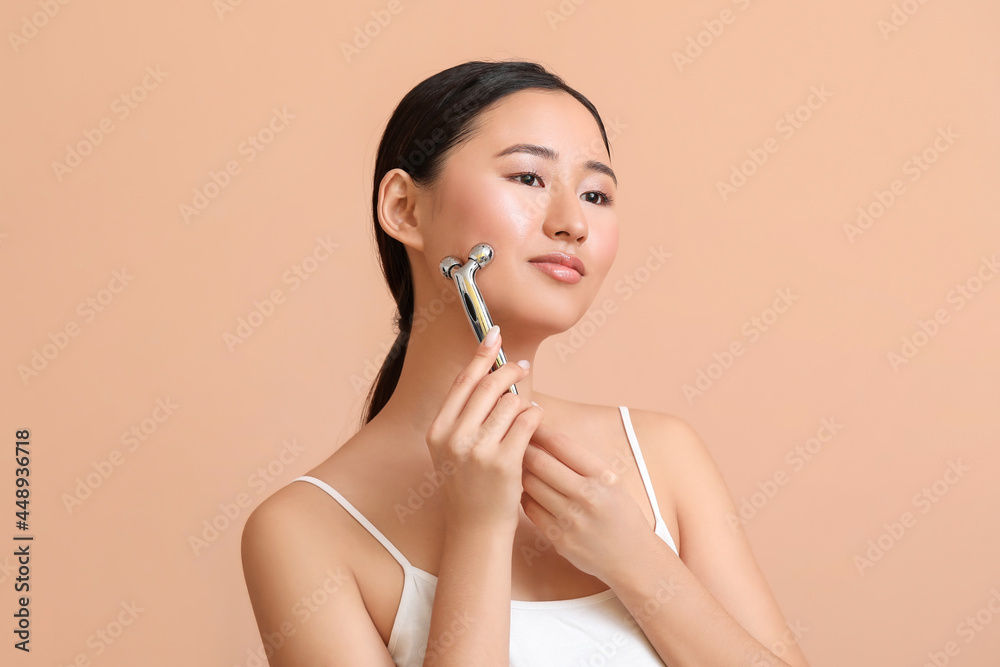 Beautiful young woman with massage tool on color background Beautiful young woman with massage tool on color background