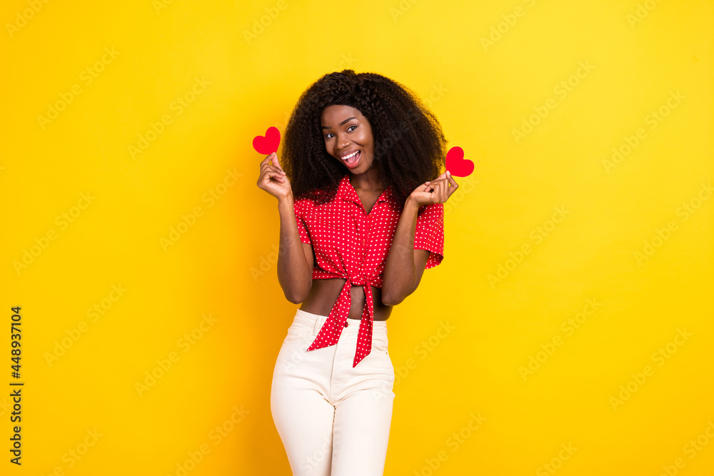 Portrait of attractive cheerful girl holding in hands small little heart shape isolated over bright yellow color background Portrait of attractive cheerful girl holding in hands small little heart shape isolated over bright yellow color background