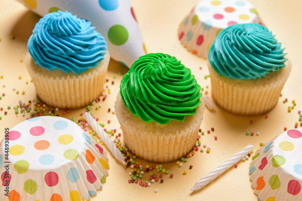Composition with tasty Birthday cupcakes, party hat and candles on color background, closeup