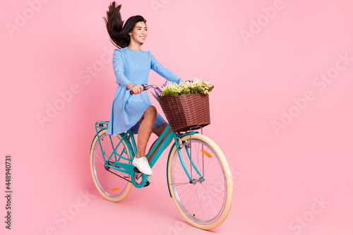 Full length profile side photo of young girl happy positive smile ride bicycle fly air hair isolated over pastel color background © deagreez