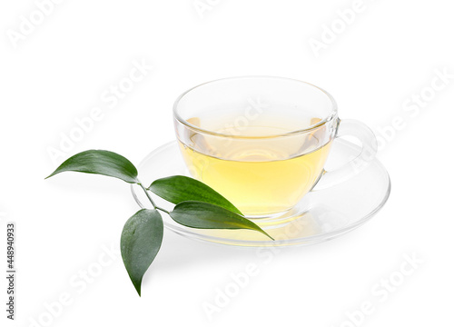 Glass cup of tea and green leaves on white background