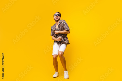 Full length photo of sweet charming young guy wear leopard outfit dark eyewear smiling dancing isolated yellow color background