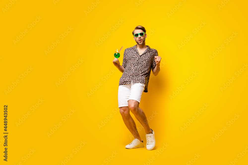 Full length photo of sweet attractive young gentleman dressed print shirt glasses drinking cocktail isolated yellow color background Full length photo of sweet attractive young gentleman dressed print shirt glasses drinking cocktail isolated yellow color background