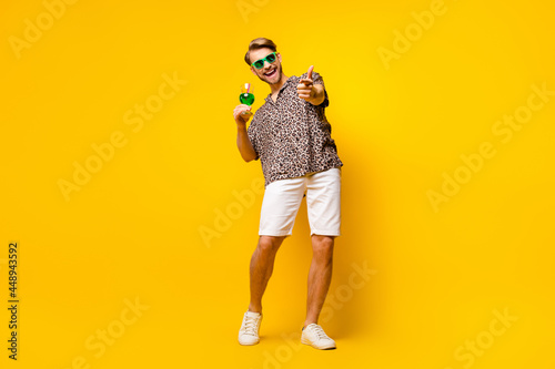 Full length photo of attractive cute gentleman dressed print shirt glasses drinking cocktail pointing you isolated yellow color background
