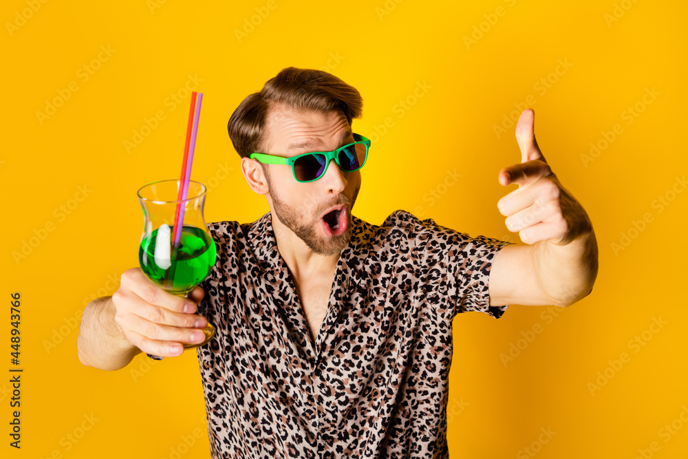 Photo of funky impressed gentleman dressed print shirt dark glasses drinking cocktail pointing you isolated yellow color background