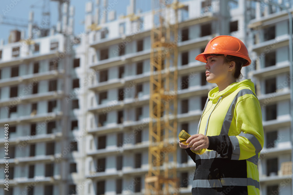 An engineer in a green construction hoodie and helmet manages the construction process by inspecting the construction process An engineer in a green construction hoodie and helmet manages the construction process by inspecting the construction process