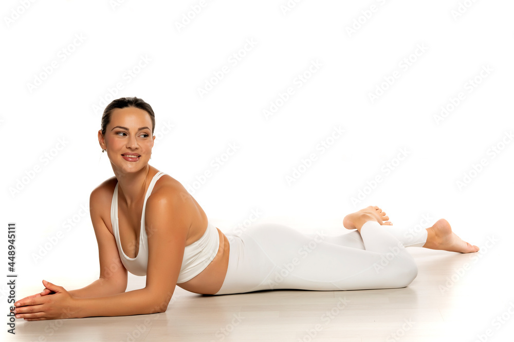 a young beautiful woman in white sportswear is resting lying on the floor a young beautiful woman in white sportswear is resting lying on the floor