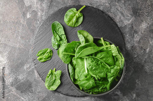 Bowl with fresh spinach leaves on grey background