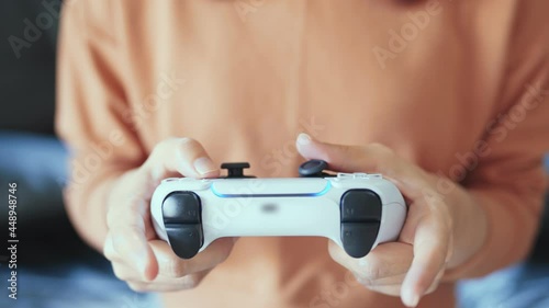 Closeup - Hands holding controller presses buttons on game joystick and play TV game. photo