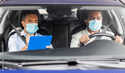 driver courses, health and people concept - young man and driving school instructor in mask with clipboard in car © Syda Productions