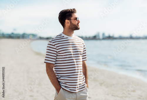 summer holidays and people concept - portrait of young man in sunglasses on beach in tallinn, estonia photo