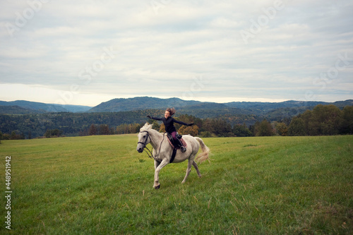 Girl with horse. The girl horseback riding in bautiful landscape. Girl in the saddle. The girl ride with the horse gallops. Horse riding without holding.
