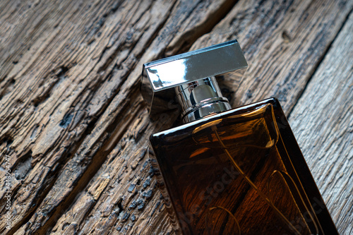 Men's perfume bottle on a weathered wooden background. Eau de toilette with a woody scent concept. photo