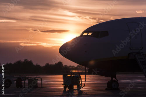 Obraz na płótnie Parked airplane side view backlit, sunset time.