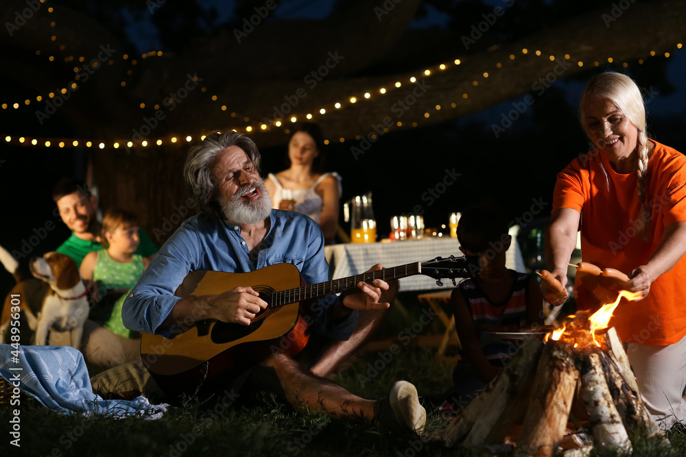 Happy family roasting sausages on fire outdoors Happy family roasting sausages on fire outdoors