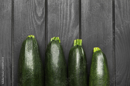 Fresh zucchini squashes on dark wooden background