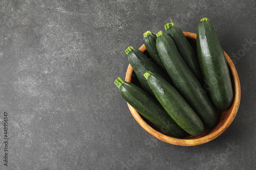 Billede på lærred Bowl with fresh zucchini squashes on dark background