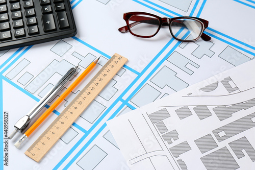 Office stationery and eyeglasses on cadastral maps of territory with buildings