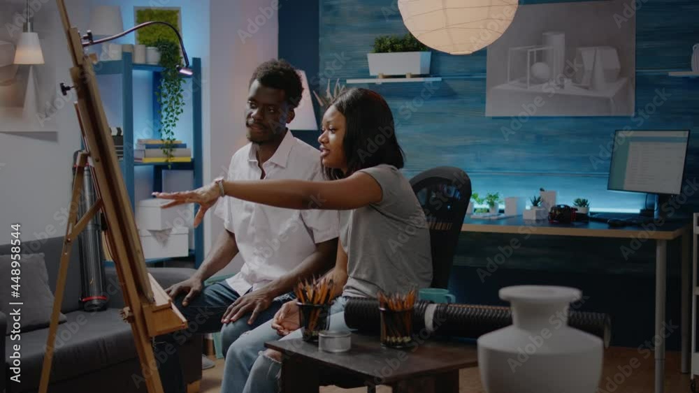 Black artistic couple talking about drawing technique at workshop studio. Woman and man of african american ethnicity working on successful innovative masterpiece for vase design