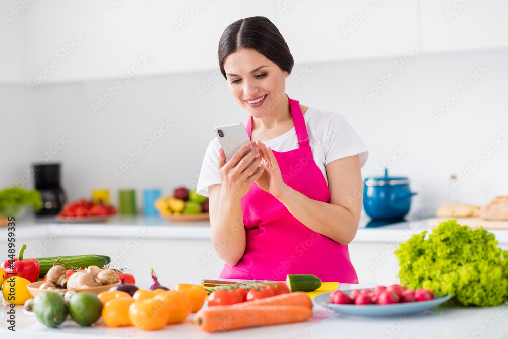 Photo portrait woman in apron cooking vegetable salad using smartphone Photo portrait woman in apron cooking vegetable salad using smartphone