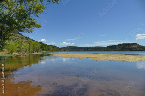 panoramic view of lake with reflection under blue sky picturing harmony and tranquility with copy space in sky