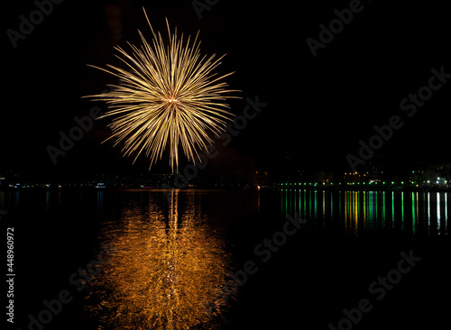 night illuminated by fireworks display on Lake Lugano for August 15th, Porto Ceresio, Lombardy, Italy.