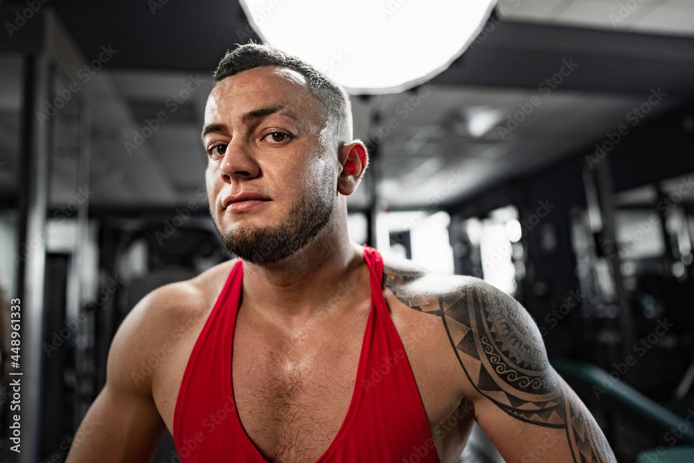 Fototapeta premium Portrait of man bodybuilder in red shirt in gym