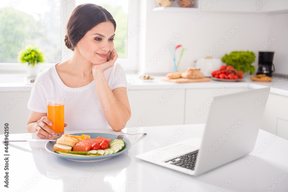 Photo of charming shiny lady wear white t-shirt enjoing breakfast watching video modern device smiling indoors room home house