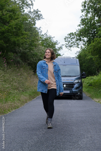 Cheerful young woman walking along the road in nature. Vertical photo.