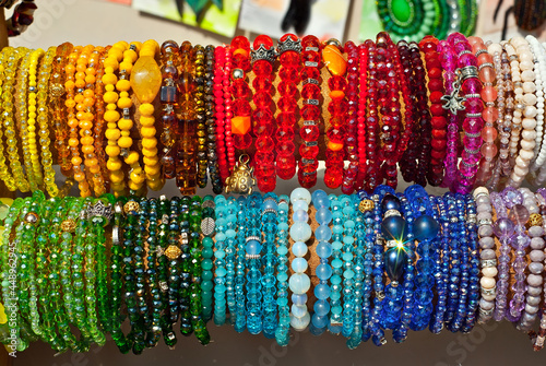 Multicolored decorations at the fair. Many bracelets with stones and jewelry. © Ivan