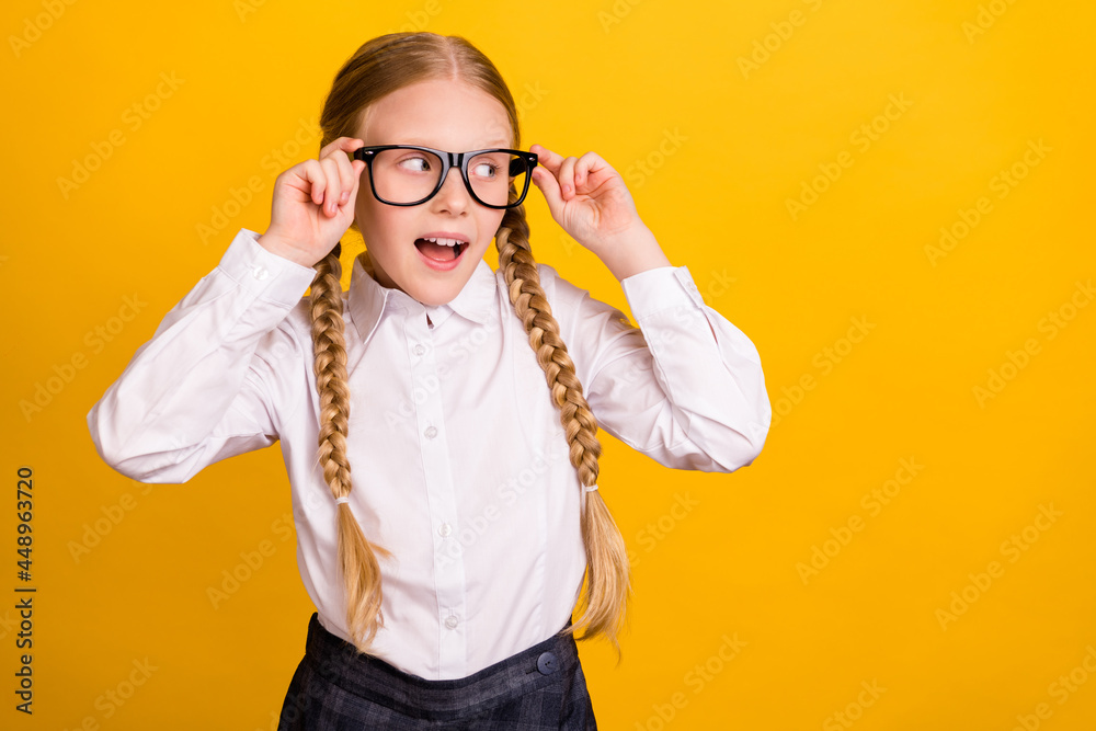Photo of cheerful pupil touch eyewear look interested empty space isolated on yellow color background Photo of cheerful pupil touch eyewear look interested empty space isolated on yellow color background