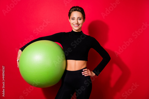 Portrait of attractive cheerful girlholding fitball body building yoga abt isolated over bright red color background photo