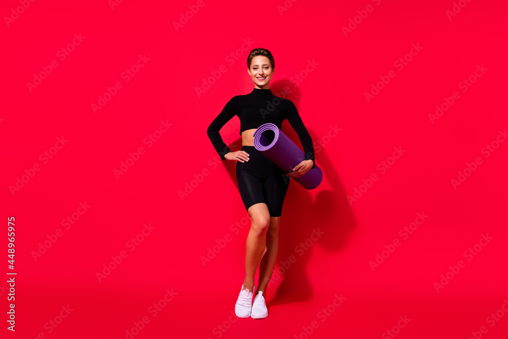 Full length body size view of attractive cheerful girl posing holding yoga mat crossfit isolated over bright red color background