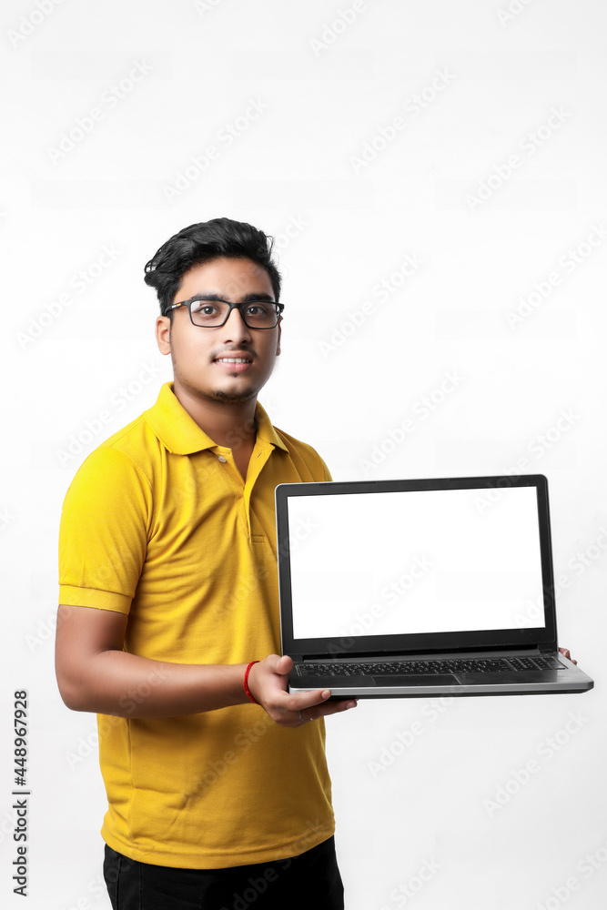 Young indian man showing laptop screen over white background. Young indian man showing laptop screen over white background.