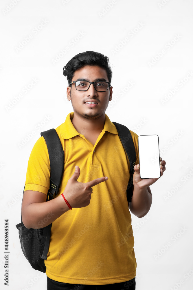 Fototapeta premium Young indian college student showing Mobile phone on white background.