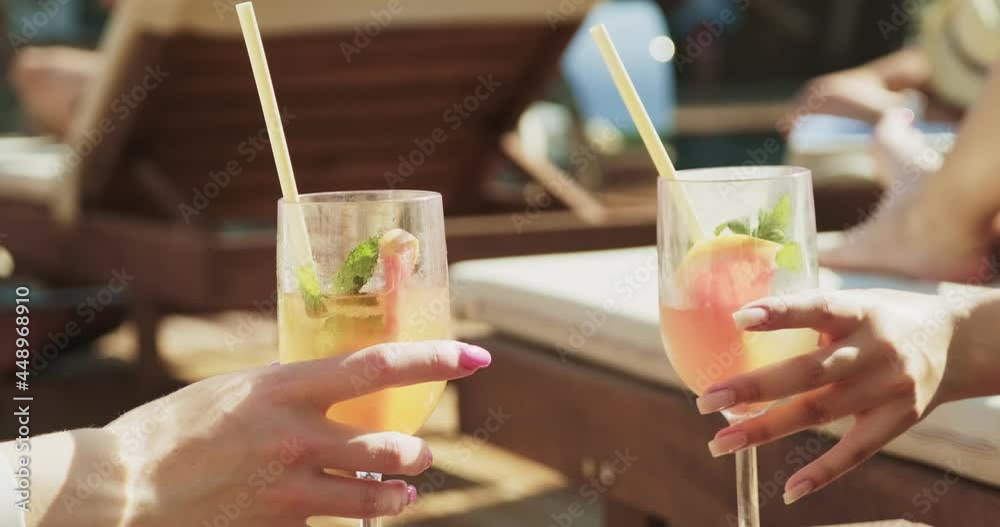 Two women in sexy swimwear are relaxing near pool. Travelling and having holiday in the luxury hotel. Two girls with alcohol beverages having fun together on holiday resort Two women in sexy swimwear are relaxing near pool. Travelling and having holiday in the luxury hotel. Two girls with alcohol beverages having fun together on holiday resort