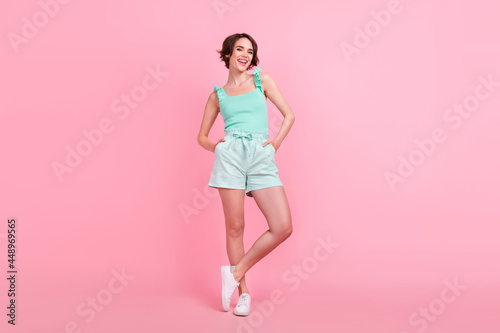Full body photo of funky short hairdo young lady stand wear teal top shorts isolated on pink color background © deagreez
