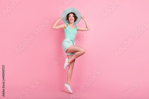 Full length photo of cute short hairdo young lady jump wear teal top shorts hat isolated on pink color background