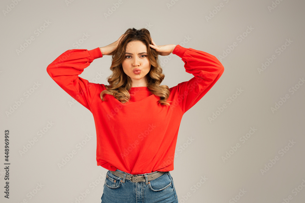 curly woman with duck face adjusting hair isolated on grey curly woman with duck face adjusting hair isolated on grey