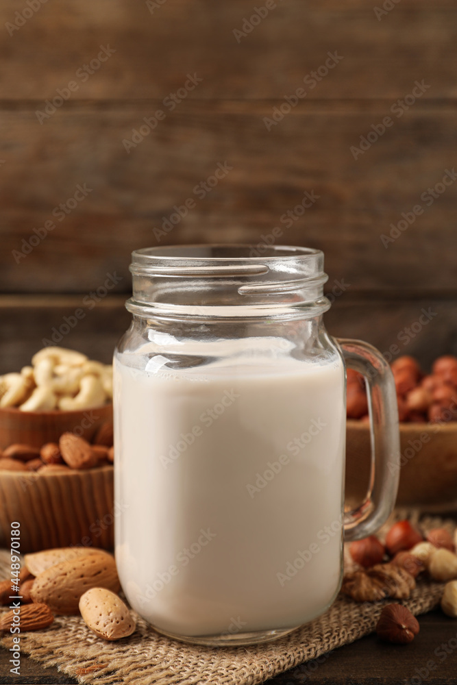 Vegan milk and different nuts on wooden table Vegan milk and different nuts on wooden table