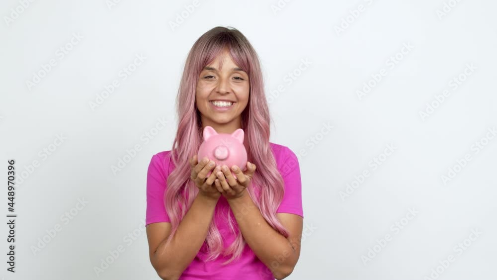 Young woman with pink hair unhappy and holding a piggybank over isolated background Young woman with pink hair unhappy and holding a piggybank over isolated background