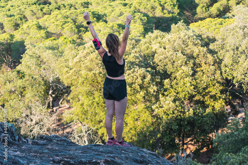 Rear view of a caucasian young woman doing victory gesture in the mountain.
