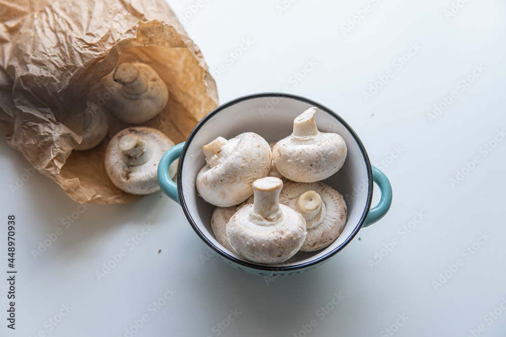 Some wild mushroom on a bowl and in a brown paper bag over a white background